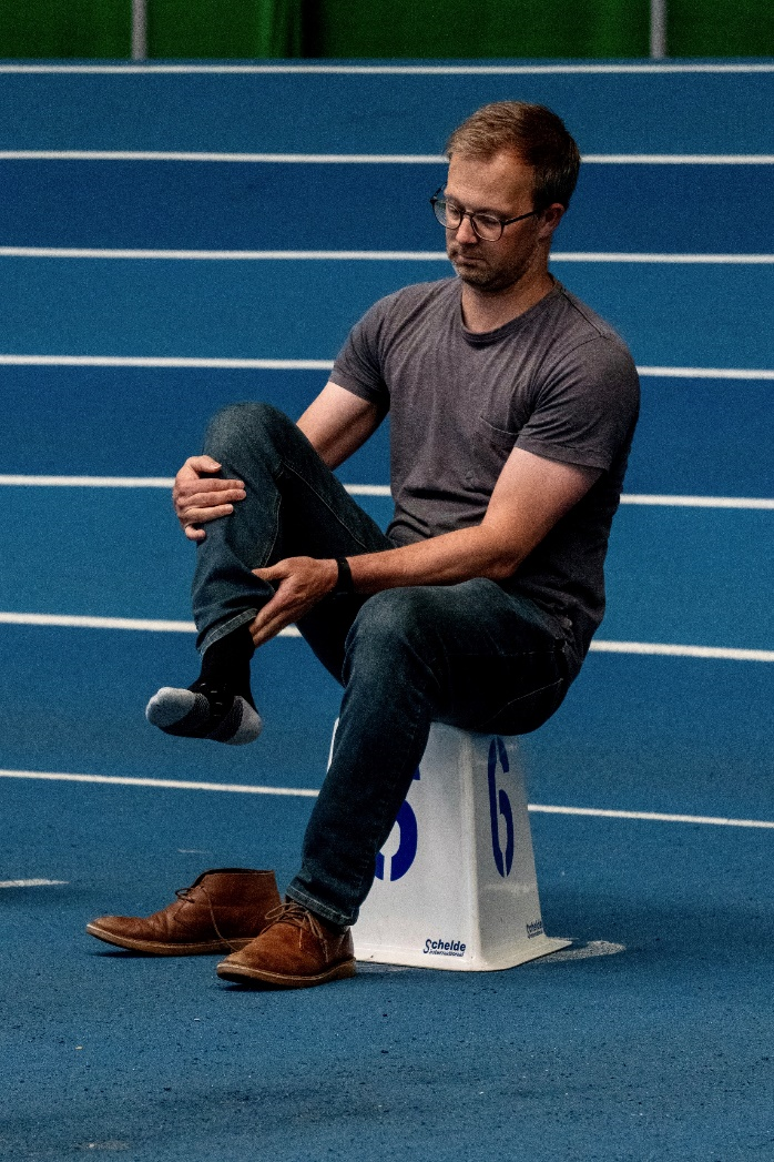 Man sat on a numbered cone taking off shoe - balanced